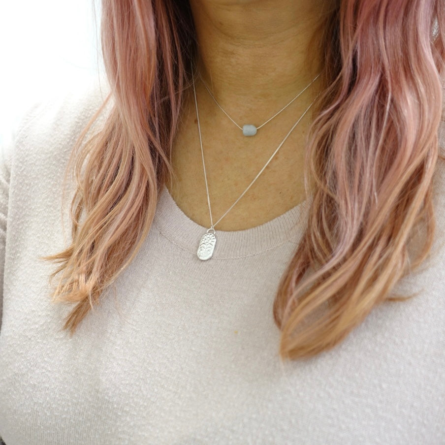 A model wearing a dainty silver Moon and Dusk soziac necklace with the symbol for zodiac sign gemini on it