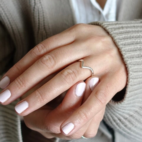 A hand wearing a Moon & Dusk sterling silver wishbone ring