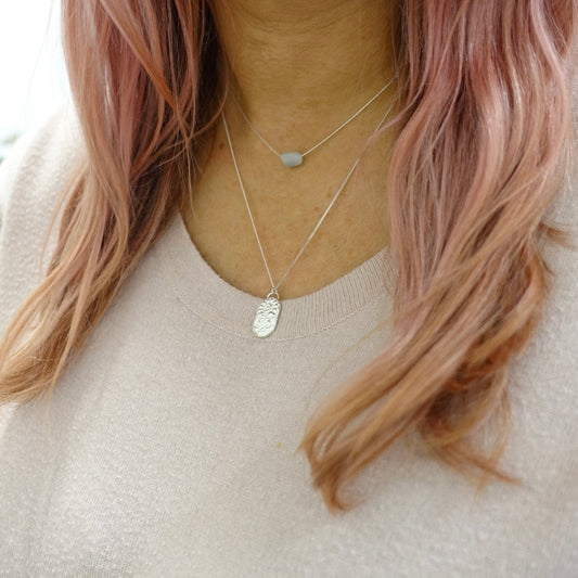 A dainty Moon and Dusk zodiac pendant with the symbol for Libra, worn by a model
