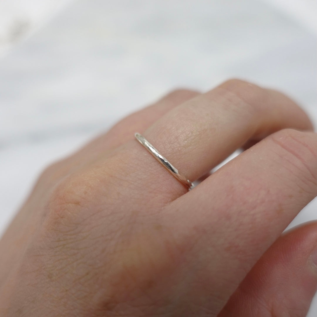 A models hand positioned so you can see a beautifully dainty Moon and Dusk Silver stacking ring
