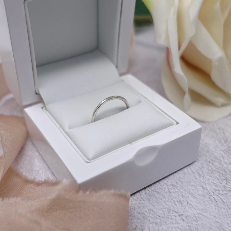 A white box is nestled in amongst some soft pink silk ribbon. Inside the box is a sparkling textured silver Moon and Dusk stacking ring