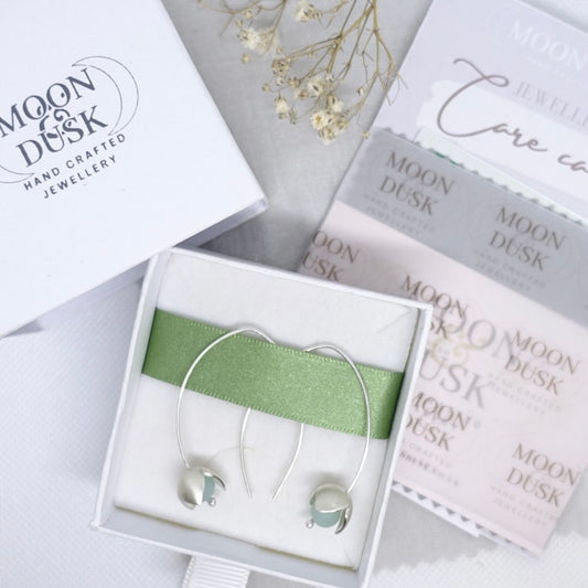 Handmade silver and gemstone flower threader earrings in a white box with Moon & Dusk care kit