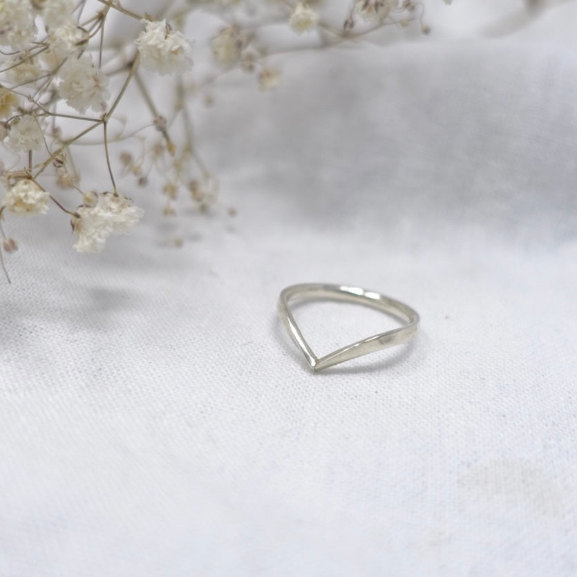 A Moon & Dusk sterling silver wishbone ring on a soft white linen background